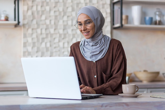 Young beautiful muslim woman in hijab and glasses studying remotely using laptop student woman in