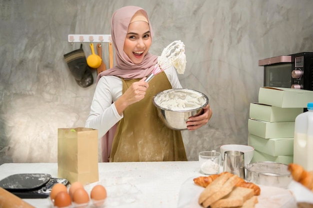 Young beautiful muslim woman is baking in her kitchen bakery and coffee shop business