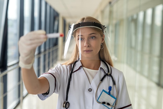 Young beautiful nurse stands in the hallway in uniform and holds blood samples. Medicine concept