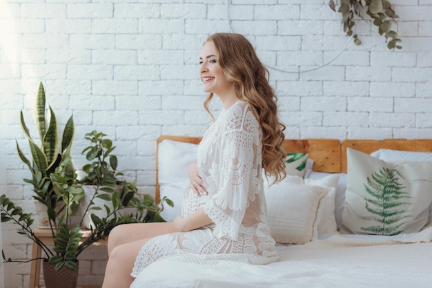 Young beautiful pregnant woman at home pregnancy rest people and expectation concept Being pregnant is one of the greatest miracles in the world happy pregnant woman sitting on bed in bedroom