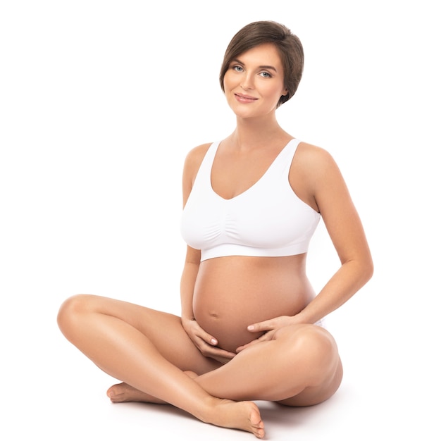 Young and beautiful pregnant woman on white wall