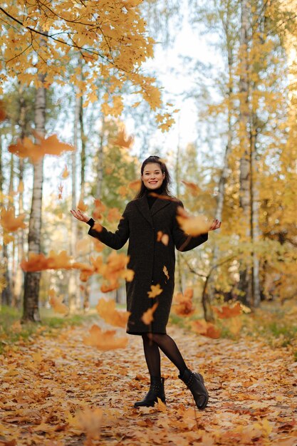 Young beautiful pregnant woman with dark hair in a black tight dress and coat posing