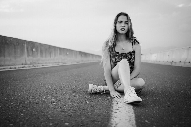 Young beautiful rebel woman on empty road at sunset