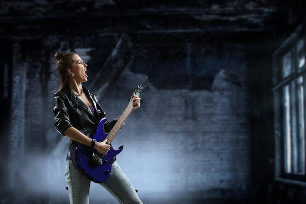 Photo young and beautiful rock girl playing the electric guitar. mixed media