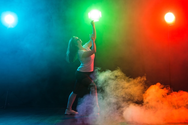 Young beautiful slim girl dancing jazz-funk on a black studio background.