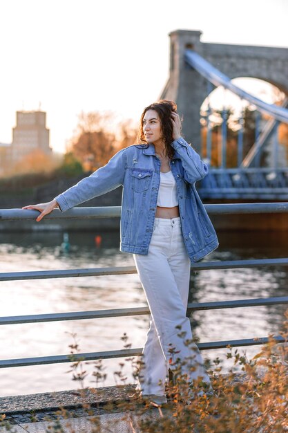 Young beautiful smiling hipster woman in trendy summer clothes Sexy carefree model posing on the europe street background at sunset Positive brunette female Cheerful and happy