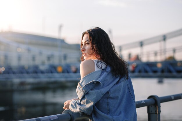 Young beautiful smiling hipster woman in trendy summer clothes Sexy carefree model posing on the europe street background at sunset Positive brunette female Cheerful and happy