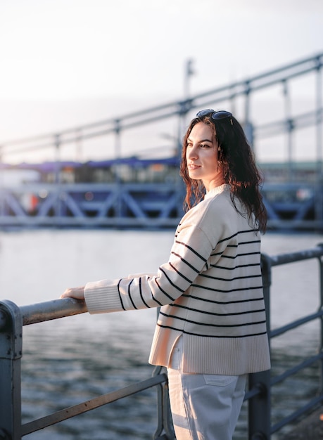 Young beautiful smiling hipster woman in trendy summer clothes Sexy carefree model posing on the europe street background at sunset Positive brunette female Cheerful and happy