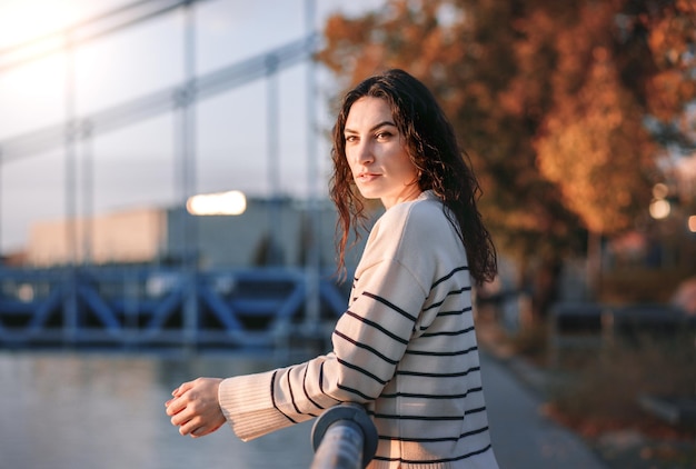 Young beautiful smiling hipster woman in trendy summer clothes Sexy carefree model posing on the europe street background at sunset Positive brunette female Cheerful and happy