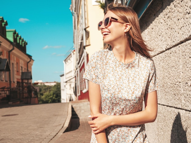 Young beautiful smiling hipster woman in trendy summer clothes Sexy carefree woman posing on the street background at sunset Positive model outdoors Cheerful and happy in sunglasses