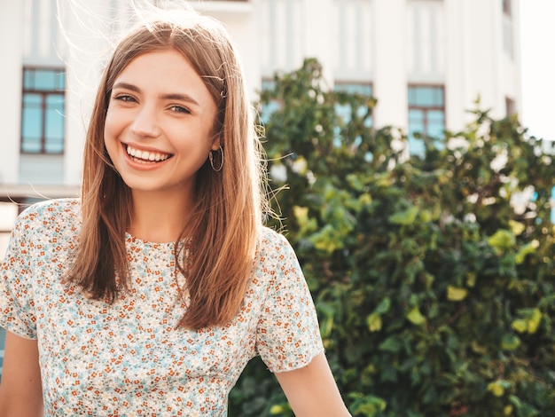 Young beautiful smiling hipster woman in trendy summer white tshirt Sexy carefree woman posing on the street background at sunset Positive model outdoors Cheerful and happy