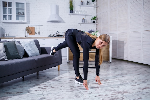 Young beautiful sports girl in leggings and a top does exercises at home on the couch. Healthy lifestyle. The woman goes in for sports at home.