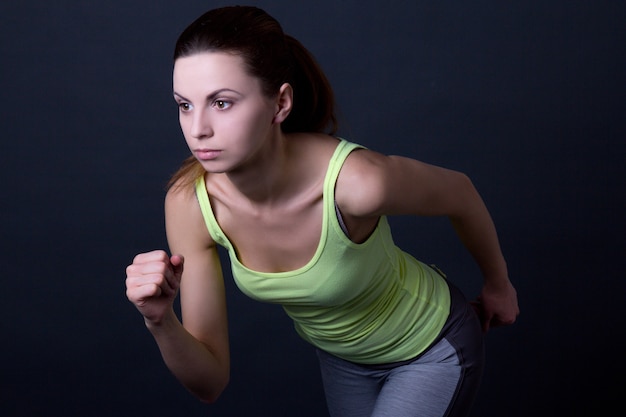 Young beautiful sporty woman running over grey background