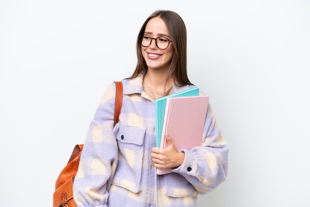 Young beautiful student woman isolated on white background looking to the side and smiling