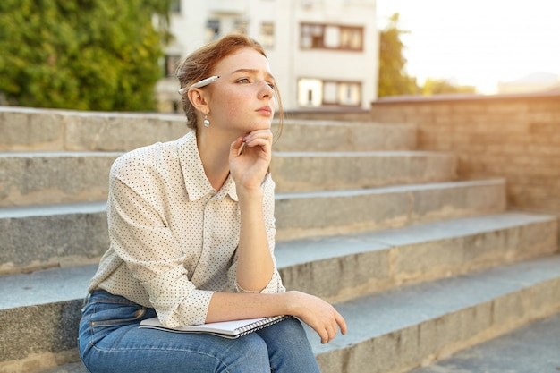 Young beautiful student writes an essay in her notebook 