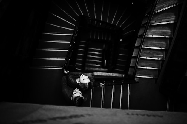 Young beautiful stylish couple in a red dress in big wooden vintage stairs