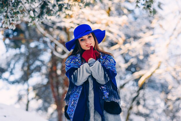 Young beautiful stylish woman in blue hat and scarf walking in the park 