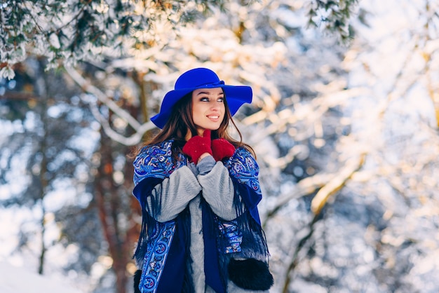 Young beautiful stylish woman in blue hat and scarf walking in the park 