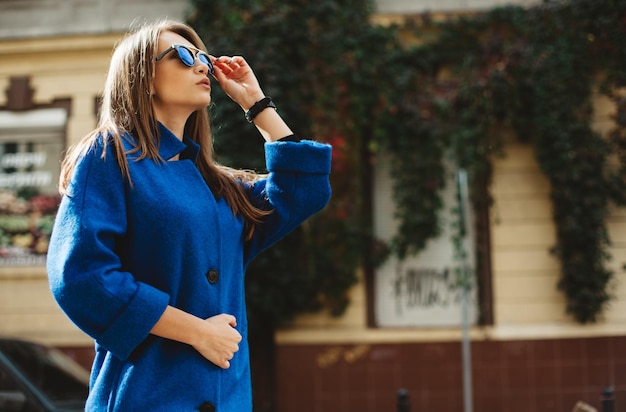 Young beautiful stylish woman walking in street in blue coat autumn fashion trend