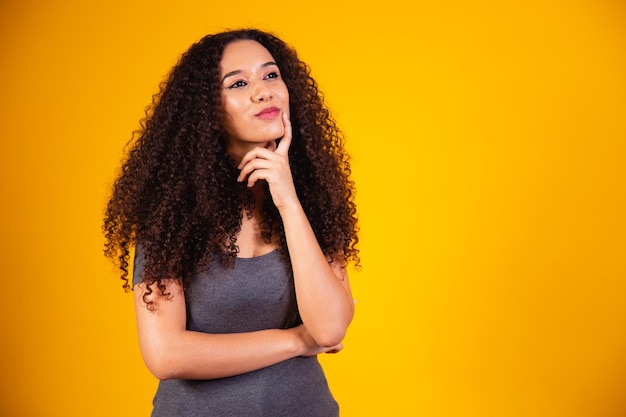 Young beautiful teen student girl dreaming thinking looking in side over yellow background.