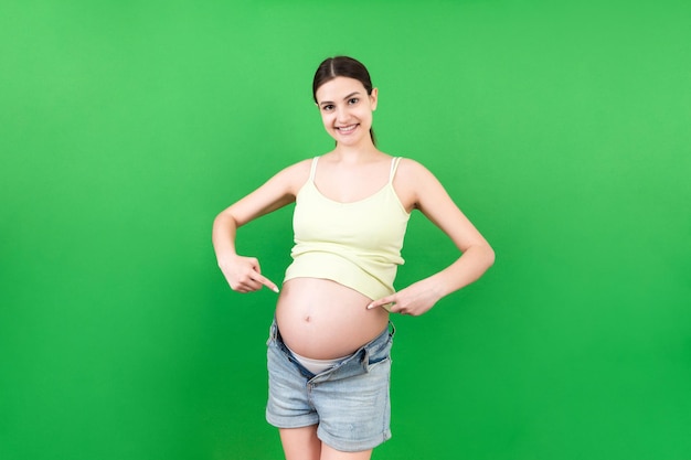 Young beautiful teenager girl pregnant expecting baby over isolated colored background smiling showing big belly