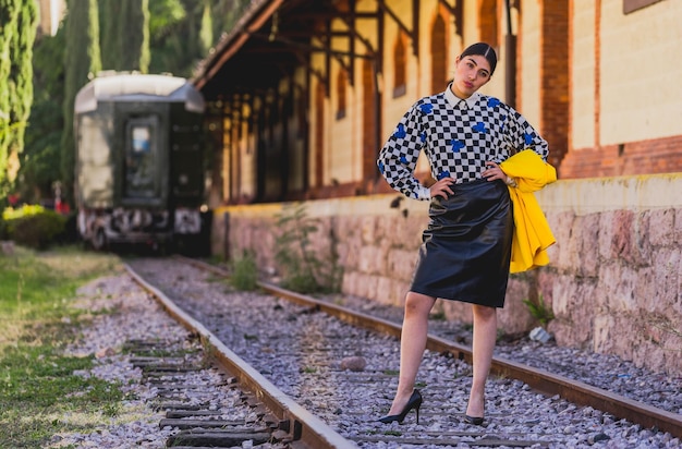 Young beautiful tourist woman in retro style in old train station, wearing 
yellow jacket and black.