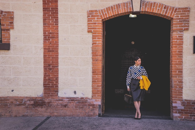 Young beautiful tourist woman in retro style in old train station, wearing 
yellow jacket and black.