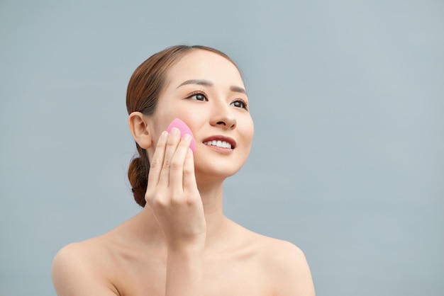 Young beautiful woman applying her makeup