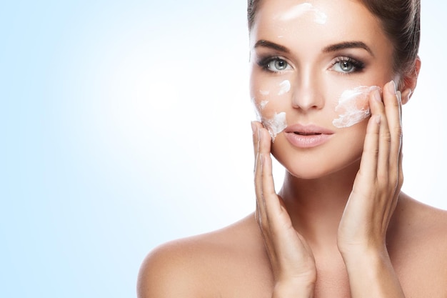 Young and beautiful woman applying moisturizing cream on her face