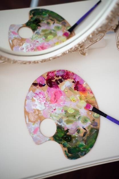 Young beautiful woman artist painting at home pink peonies