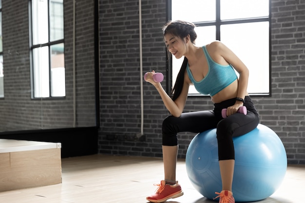 Young beautiful woman asian doing exercises with dumbbell at gym 