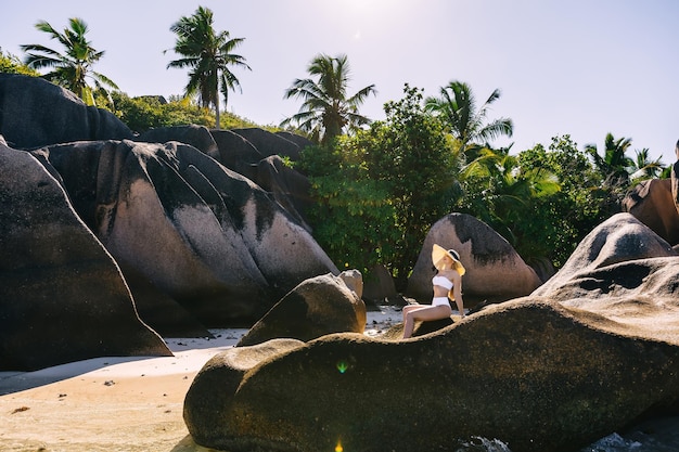 Photo young beautiful woman on the beach in a big hat against big rocks background