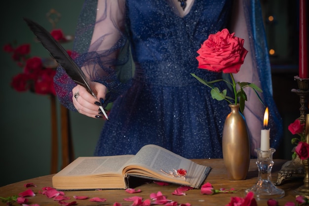 Young beautiful woman in blue vintage dress with book on table in dark room