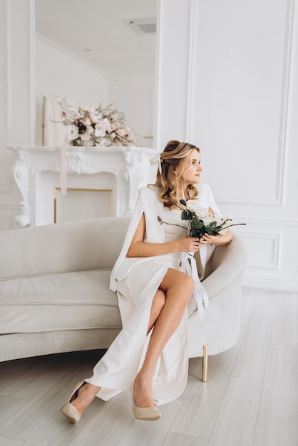 young beautiful woman bride in a wedding dress with a bouquet of flowers in a bright interior