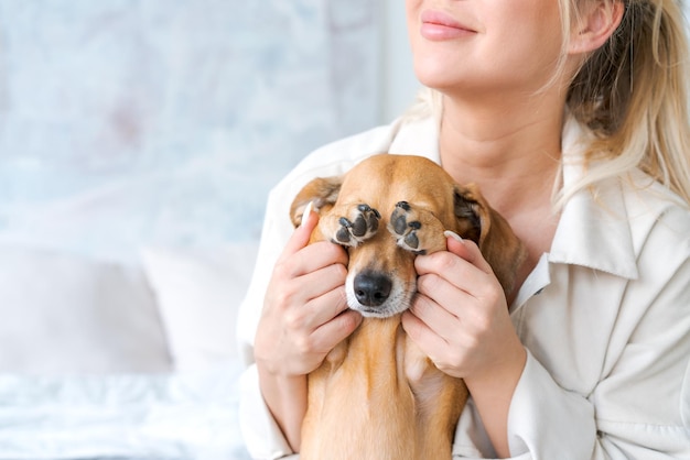 A young beautiful woman in casual clothes hugs and pets her beloved dog sitting