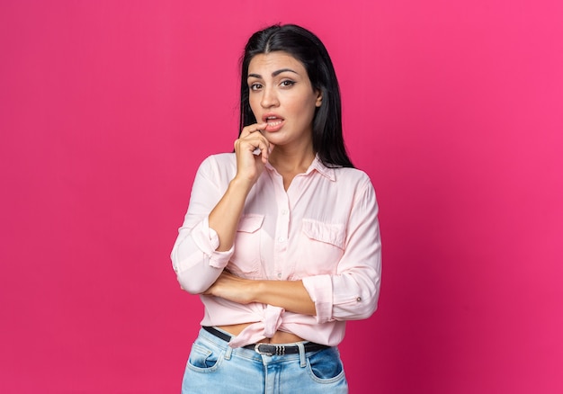 Young beautiful woman in casual clothes puzzled standing on pink