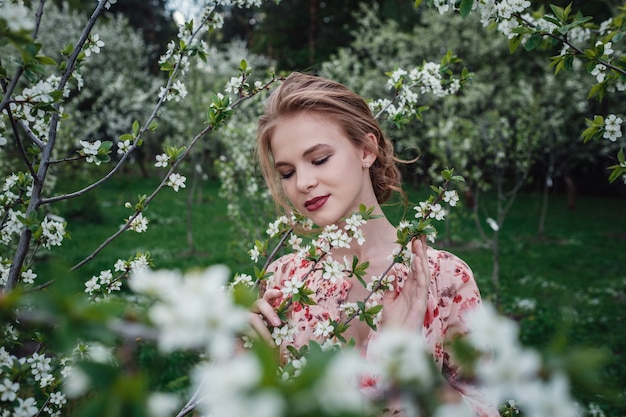 Young beautiful woman in the cherry-blossoming garden.