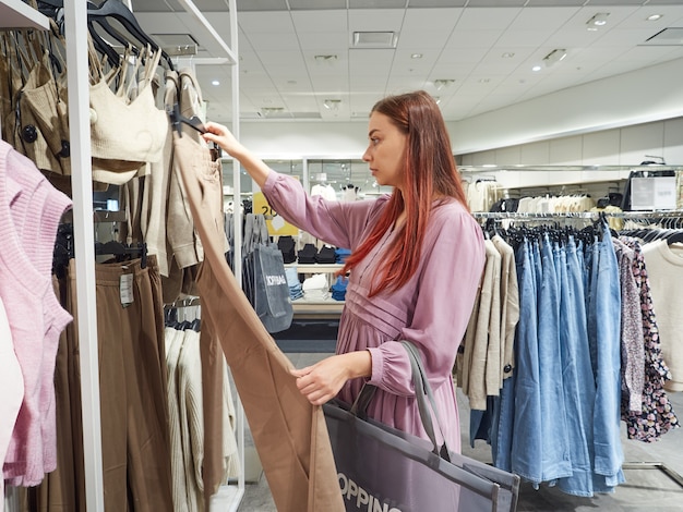 Young beautiful woman chooses clothes in a fashion store.