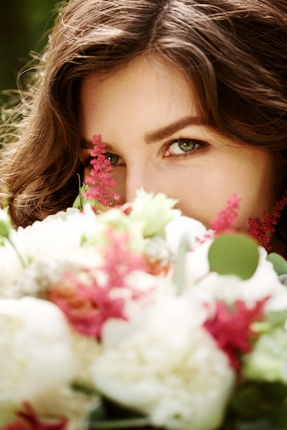 Young beautiful woman close-up behind flowers