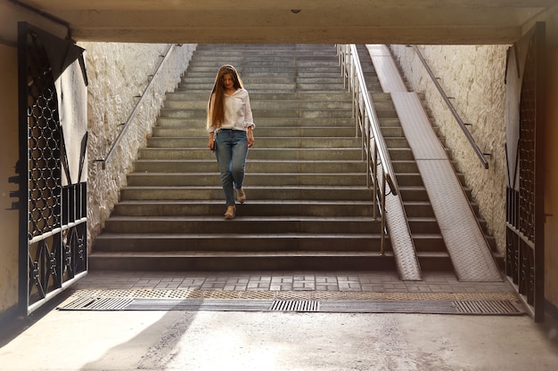 Young beautiful woman descends the steps into pedestrian underpass