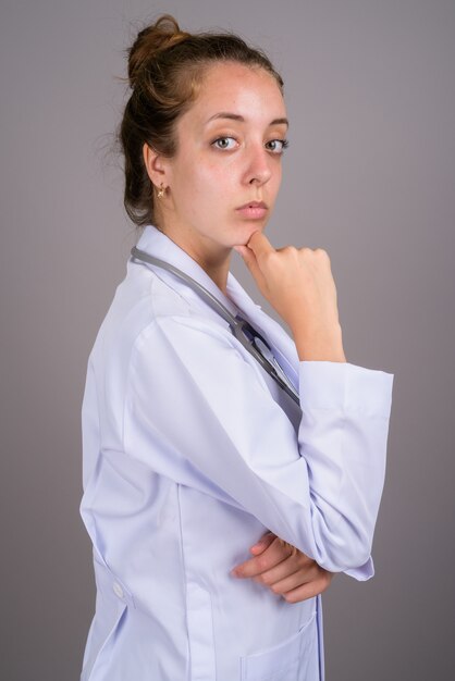 Young beautiful woman doctor against gray background