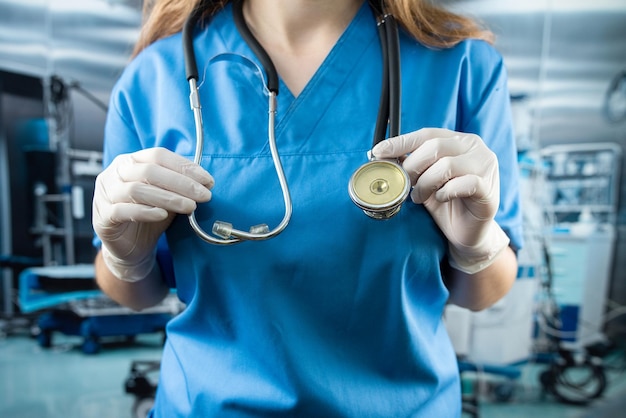 Young beautiful woman doctor in medical mask and uniform standing in operating room