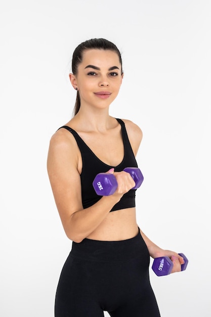 Young beautiful woman doing exercises with dumbbell in gym