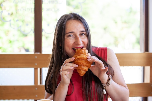 Young beautiful woman eating croissant