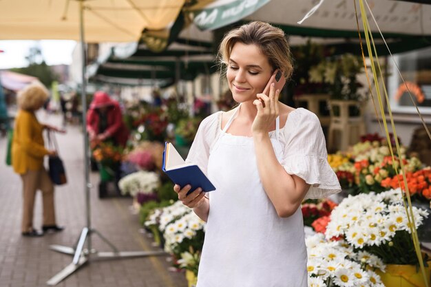 Photo young and beautiful woman florist taking order by phone in her little flower shop