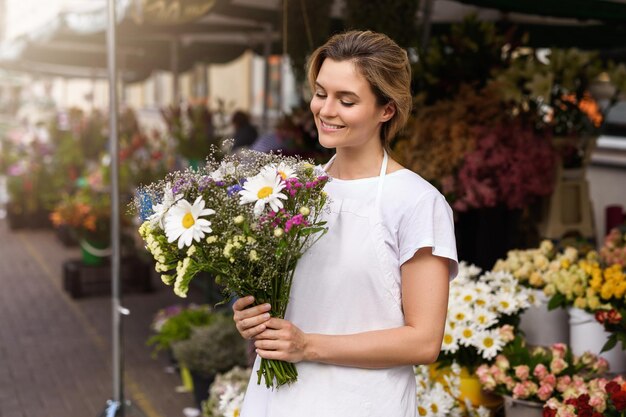 Photo young and beautiful woman florist with a bouquet of wildflowers in her little flower shop