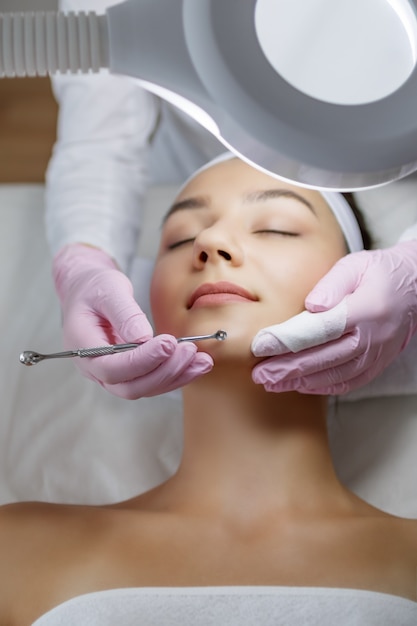 Young beautiful woman gets facial cleansing procedure in a beauty salon