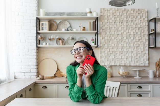 Young beautiful woman in glasses and green shirt at home got a good news read message from red