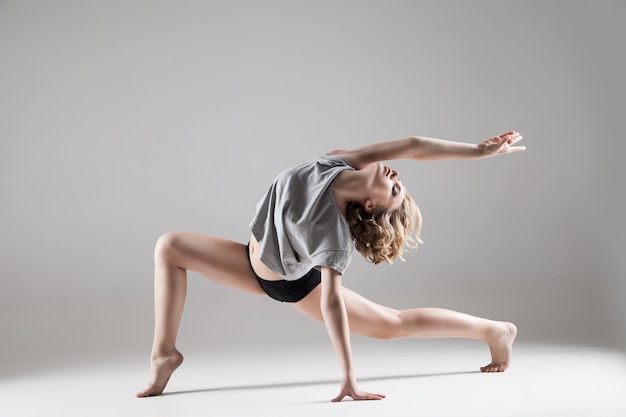 Young beautiful woman in grey T-shirt and black shorts dancing , studio series