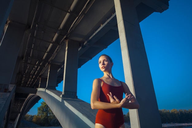 Young beautiful woman gymnast posing on bridge girder